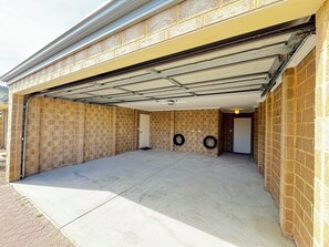 A garage with a concrete floor, brick walls, and a metal garage door. - Blissful Haven (Perth)