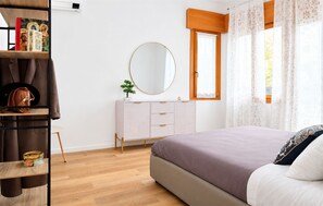 Une chambre à coucher avec un lit, une commode, un miroir, une fenêtre avec des rideaux et une étagère avec des livres et un sac à main.