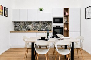 Une cuisine moderne avec des meubles blancs, un îlot central et un coin repas équipé de quatre chaises.