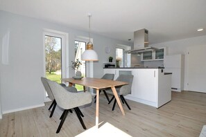Eine moderne Küche mit weißen Schränken, einem Holztisch und grauen Stühlen.