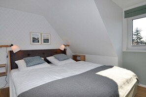 Ein Schlafzimmer mit einem Bett, zwei Nachttischen, einem Fenster und zwei an der Wand befestigten Bildern.