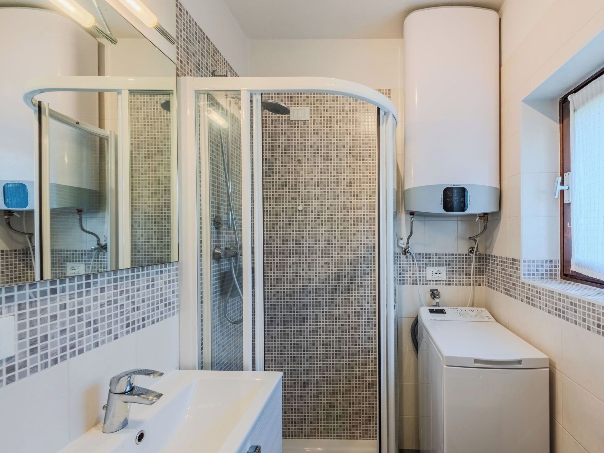 Ein modernes Badezimmer mit einer Duschkabine aus Glas, einem weißen Waschbecken und einem kleinen weißen Schrank.