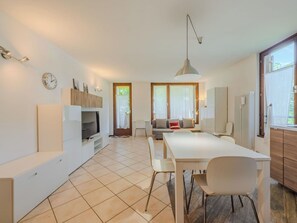 Un salon moderne avec un téléviseur, un coin salon et une table à manger.