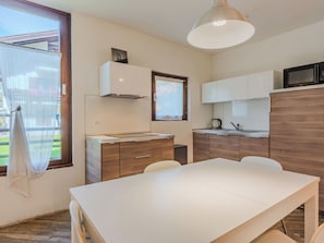 Eine moderne Küche mit weißer Arbeitsplatte, Holzschränken, einer Mikrowelle und einer Pendelleuchte.