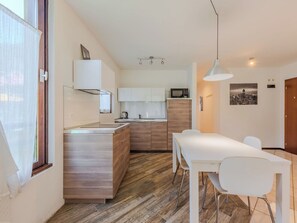 Eine moderne Küche mit einer zentralen Kochinsel, Holzschränken und einem Essbereich mit einem weißen Tisch und Stühlen.