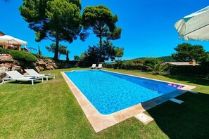 Una piscina rettangolare con superficie d'acqua cristallina, circondata da un prato curato e qualche sedia a sdraio.