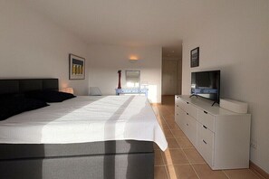 Ein Schlafzimmer mit einem großen Bett, einem Schminktisch, einem Fernseher und einem Spiegel.