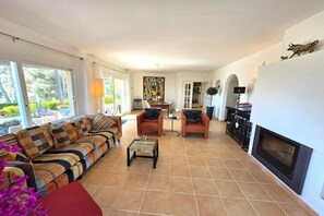Ein geräumiges Wohnzimmer mit einer Couch, Sesseln, einem Couchtisch und einem Kamin.