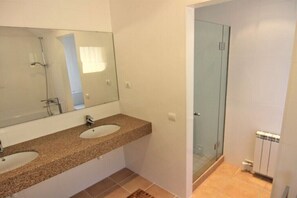 Un bagno con due lavabi, uno specchio grande e un box doccia in vetro.