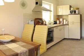 A kitchen with a dining table, chairs, a stove, and cabinets. - Holiday paradise Neubauer (Trassenheide)