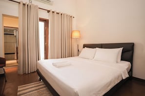 Ein Hotelzimmer mit Bett, Vorhängen, einer Lampe und einem Sessel.