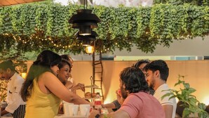 A group of people seated at a table with a white tablecloth, engaged in conversation.