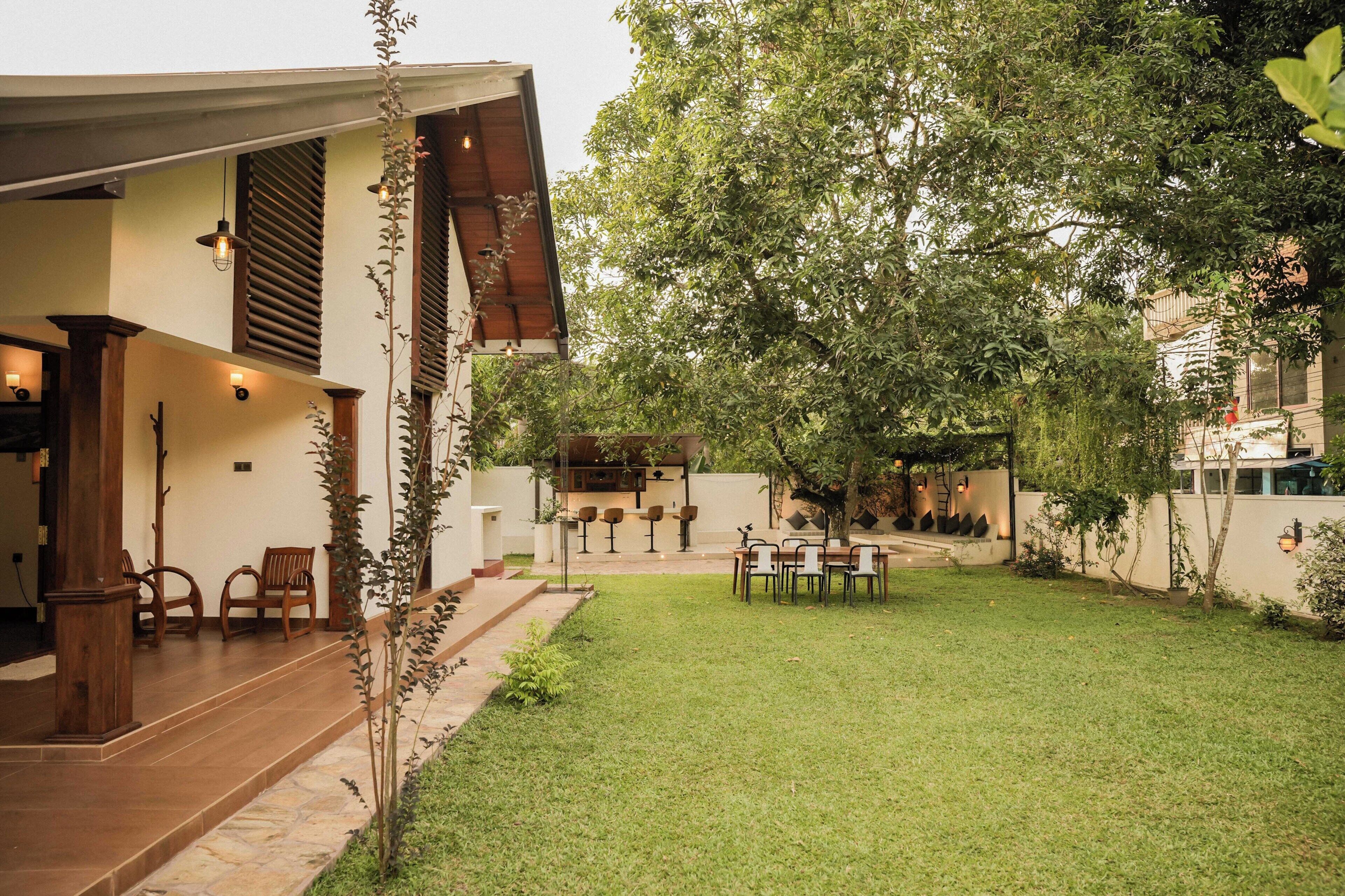 Una casa moderna con un patio, mobiliario exterior y un césped bien cuidado.