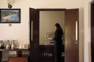 Habitación de hotel con minibar, un espejo y un cuadro con una playa.