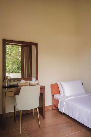 Una habitación de hotel con escritorio, silla, cama y un ventanal grande.