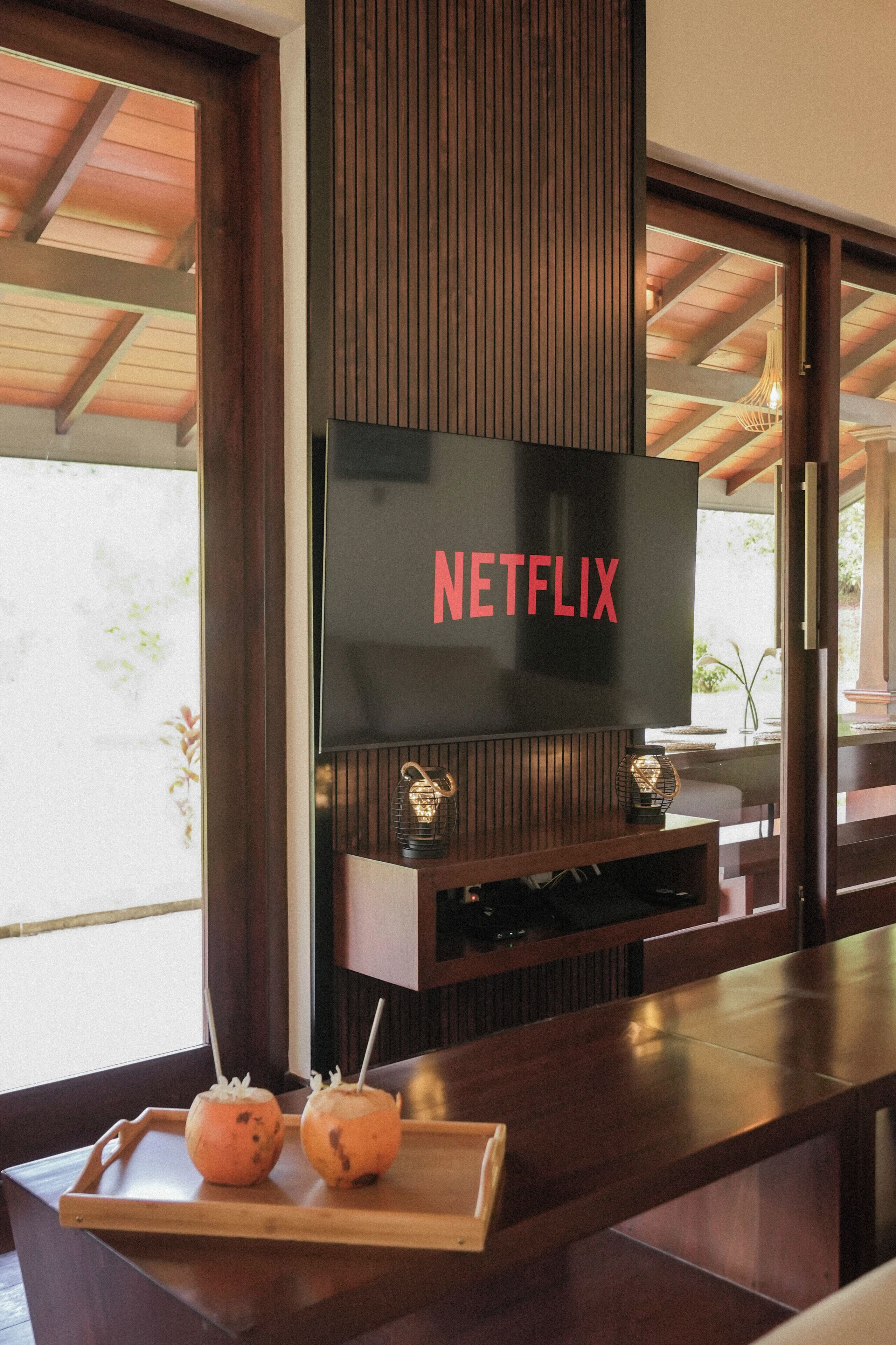 Un intérieur moderne avec un téléviseur à écran plat fixé à un mur en bois, sur lequel est affiché le logo de Netflix.