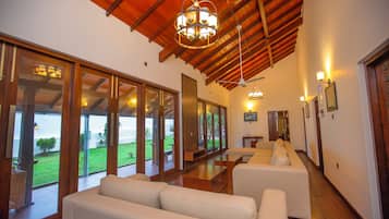 Una habitación amplia con techo alto, ventanas grandes y una zona de estar con sofás blancos.