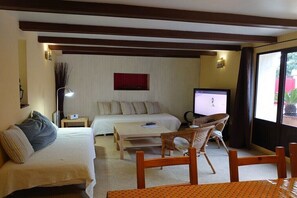 Une chambre d’hôtel avec deux lits, une télévision, une petite table et une chaise en osier.