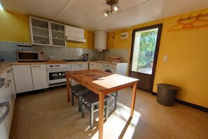 A compact kitchen with a wooden table, white cabinets, a microwave, and a window providing natural light. - Holiday apartment with 2 bedrooms (Sanary)