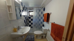 Casa de banho com lavatório, sanita e cortina de chuveiro.