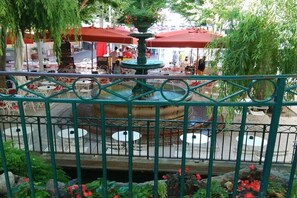 Un espace extérieur aménagé pour les repas, avec des tables et des chaises, une fontaine et une rambarde.