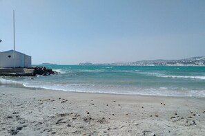 A beach with a white building, clear blue water, and distant hills. - Holiday apartment with 2 bedrooms (Sanary)