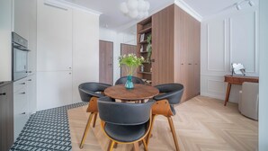 Una cocina moderna con comedor, que incluye una mesa redonda de madera, sillas negras y una planta en maceta.