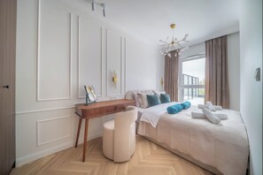 A bedroom with a bed, bedside table, chair, and a view of the outdoors. - Kierbedzia Elite, Mokotów, Warsaw (Warszawa)
