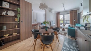 Una sala moderna con comedor, piso de madera y un ventanal grande.