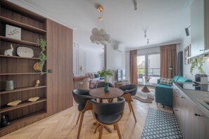 A modern living room with a dining area, wooden flooring, and a large window. - Kierbedzia Elite, Mokotów, Warsaw (Warszawa)