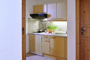 A compact kitchen with wooden cabinets, a black range hood, and a stainless steel sink. - Holiday apartment with 2 bedrooms (Chieming)