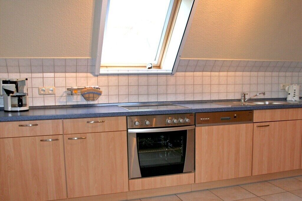 A kitchen with a built-in oven, a dishwasher, and a window above the sink.