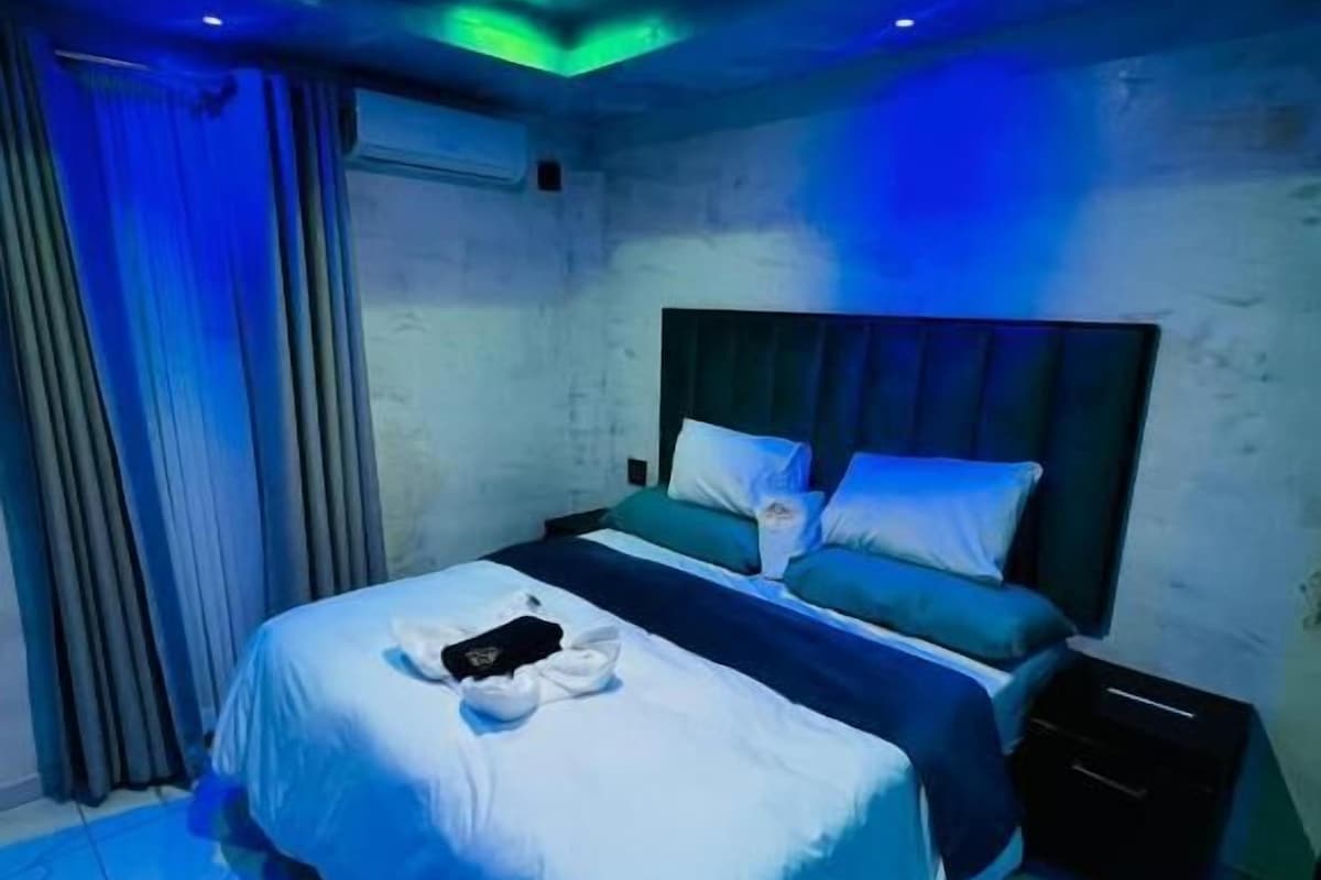 A hotel room with a bed, a nightstand, and a window with curtains.