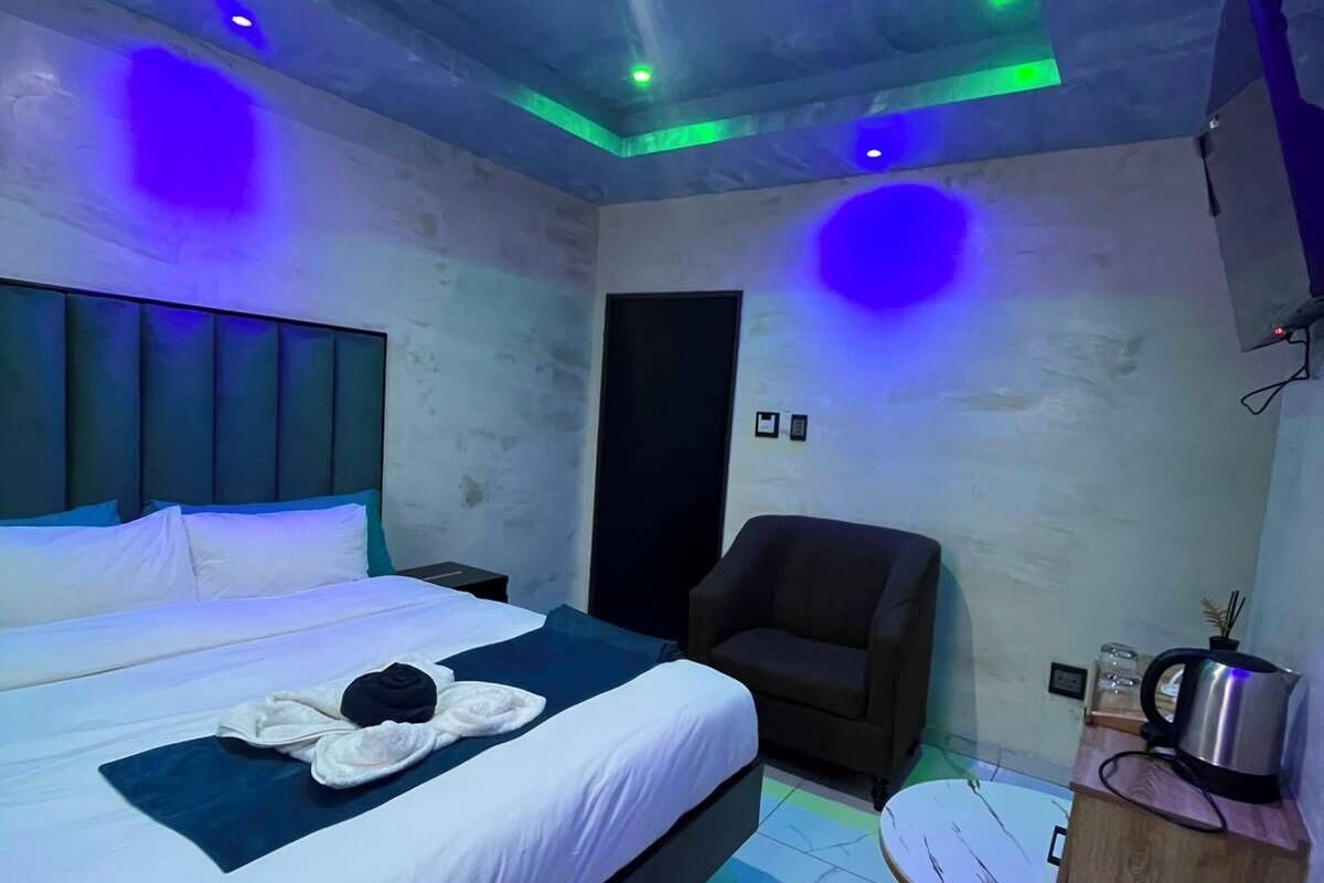 A hotel room with a bed, a chair, a desk, and a television.