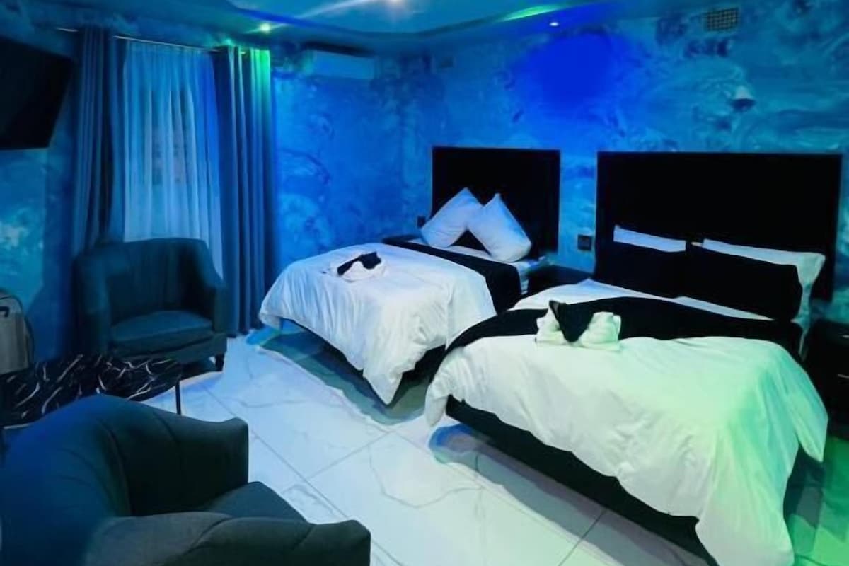 A room with two beds, a chair, and a TV.