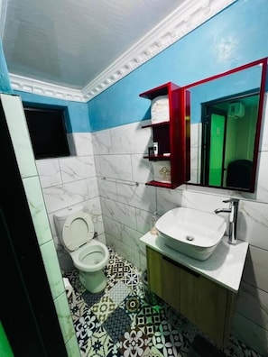 A bathroom with a toilet, sink, and mirror. - Meriambase lodge (Johannesburg)
