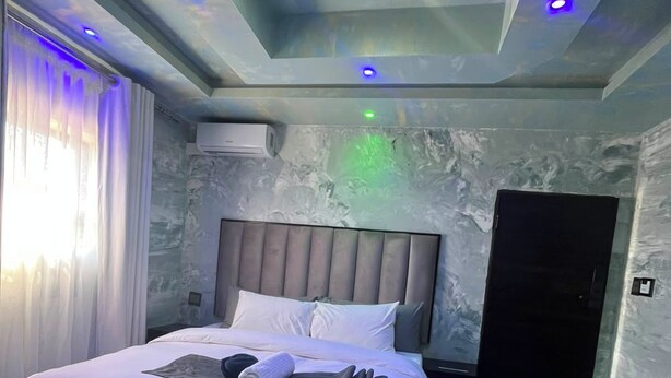 Un dormitorio moderno con cama, mesitas de noche, armario e iluminación empotrada en el techo.
