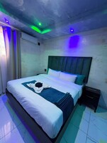 Una camera d'albergo con un letto, un comodino e una finestra con tende.
