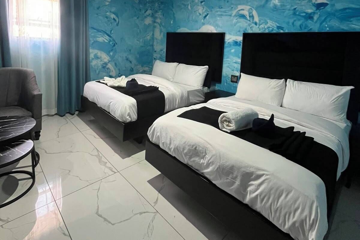 A hotel room with two beds, a chair, and a small table.