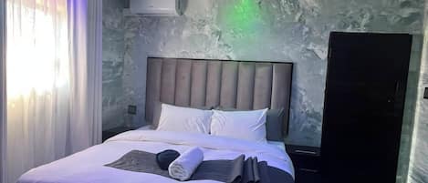 A modern bedroom with a bed, bedside tables, and a wardrobe.