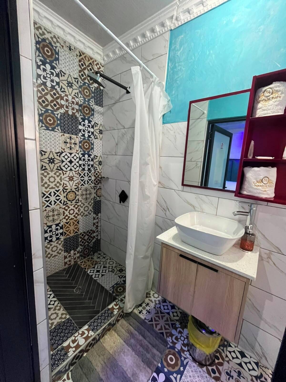 Ein Badezimmer mit Dusche, Waschbecken und Spiegel.