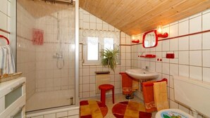 Une salle de bain avec une douche, un lavabo, des toilettes et une fenêtre.