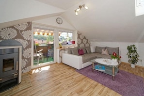 A cozy living room with a sofa, a coffee table, and a fireplace. - Holiday apartment with 1 bedroom (Frauenau)
