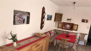 Un comedor con una mesa y sillas de madera, un banco y un camino de mesa rojo.