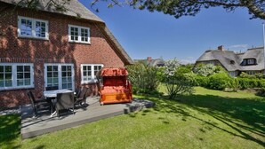 A brick house with a thatched roof, a patio with outdoor furniture, and a well-maintained lawn. - Holiday home in Kampen with swimming pool (Kampen)