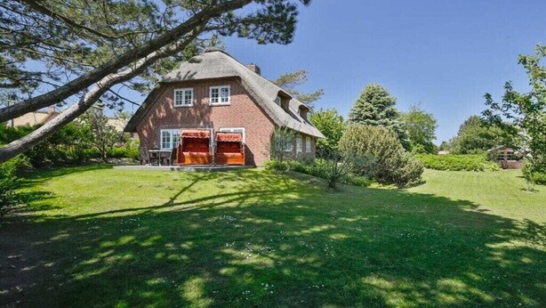 A traditional brick house with a thatched roof, a front porch, and a well-maintained lawn. - Holiday home in Kampen with swimming pool (Kampen)