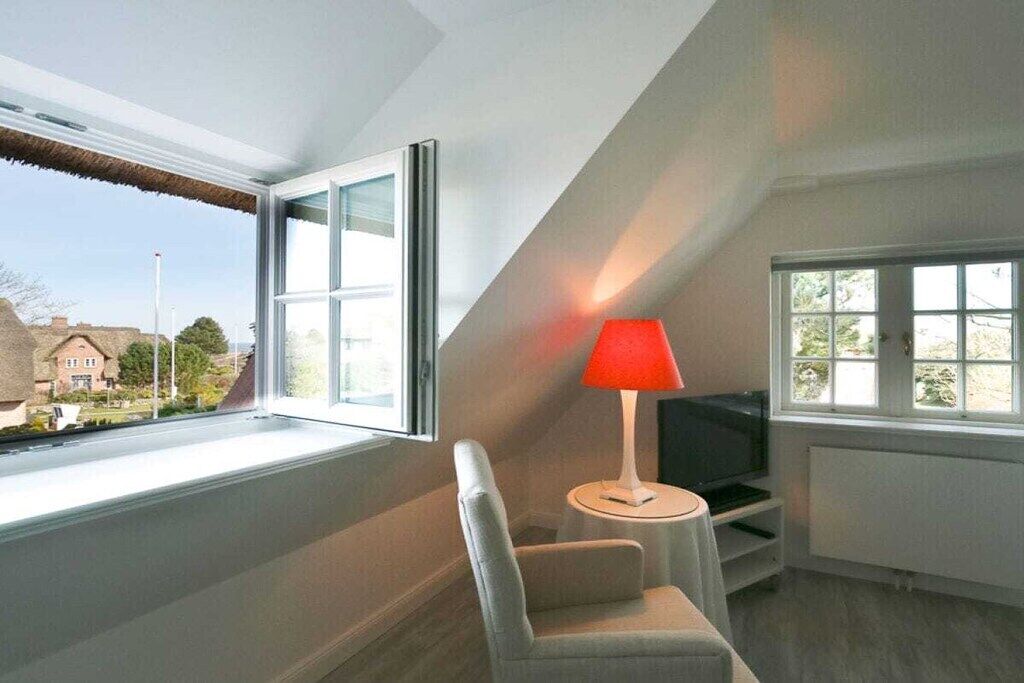 Habitació amb televisió, làmpada vermella i una cadira.