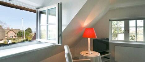 A room with a television, a red lamp, and a chair.