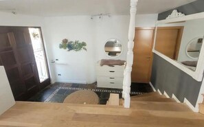 Ein Zimmer mit einer Holztreppe, einem weißen Schminktisch, einem Spiegel und einer Tür.