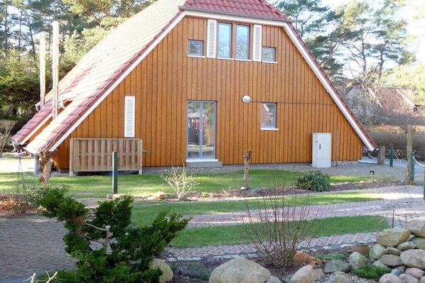Een houten huis met een schuin dak en een klein terras.